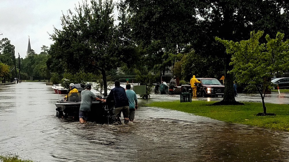 people pushing a boat in a residential area during a flood